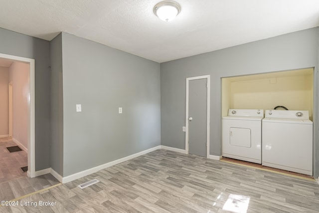 laundry room with light wood-type flooring, a textured ceiling, and washing machine and clothes dryer