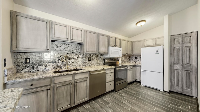 kitchen featuring light stone counters, sink, stainless steel appliances, dark hardwood / wood-style floors, and vaulted ceiling