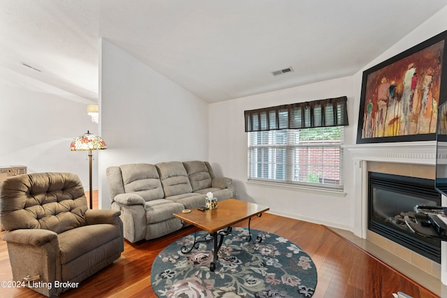 living room with vaulted ceiling, a fireplace, and hardwood / wood-style floors