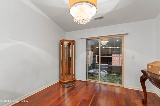 interior space with wood-type flooring, vaulted ceiling, and an inviting chandelier