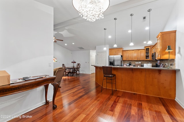 kitchen featuring hanging light fixtures, backsplash, light hardwood / wood-style floors, and stainless steel appliances