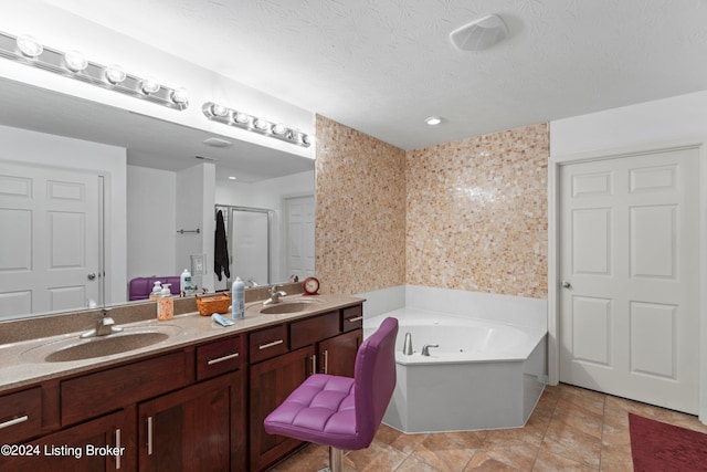 bathroom with a textured ceiling, vanity, and separate shower and tub