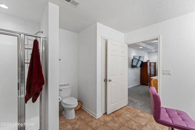 bathroom featuring a textured ceiling, walk in shower, tile patterned floors, and toilet