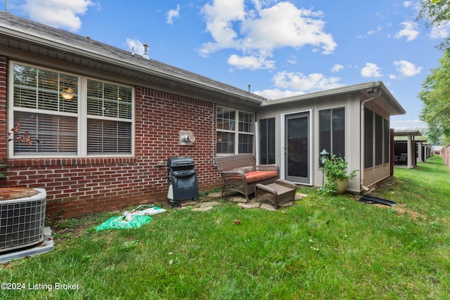 back of house featuring a sunroom, central AC unit, and a yard