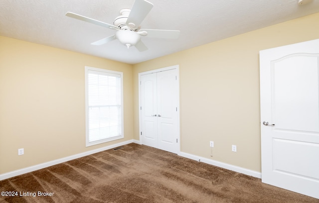 unfurnished bedroom with ceiling fan, carpet floors, a textured ceiling, and a closet