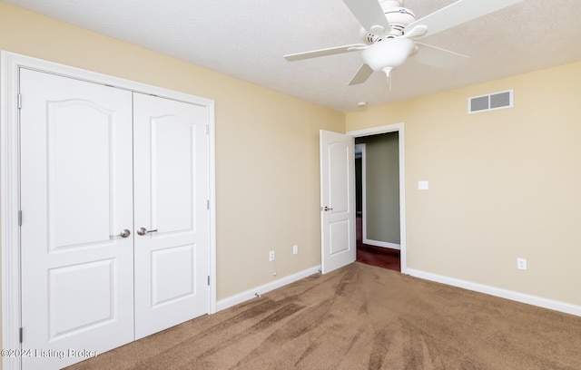 unfurnished bedroom with ceiling fan, carpet floors, a textured ceiling, and a closet