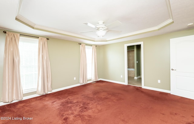 carpeted spare room with ceiling fan, a healthy amount of sunlight, a raised ceiling, and ornamental molding