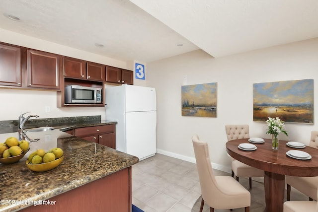 kitchen with sink, dark stone counters, and white refrigerator