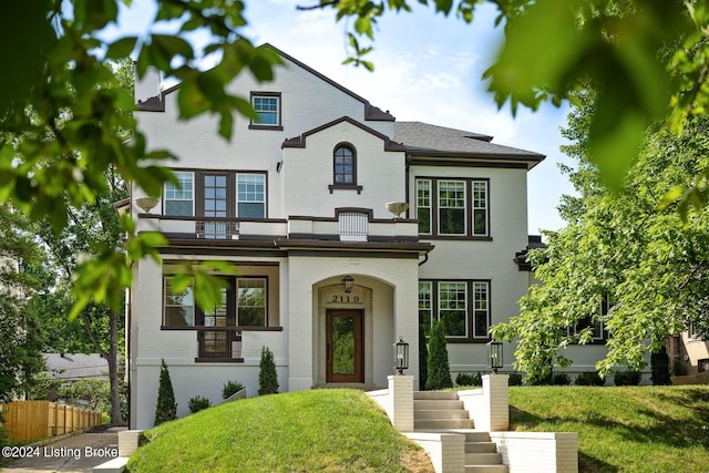 view of front of property featuring a balcony and a front lawn