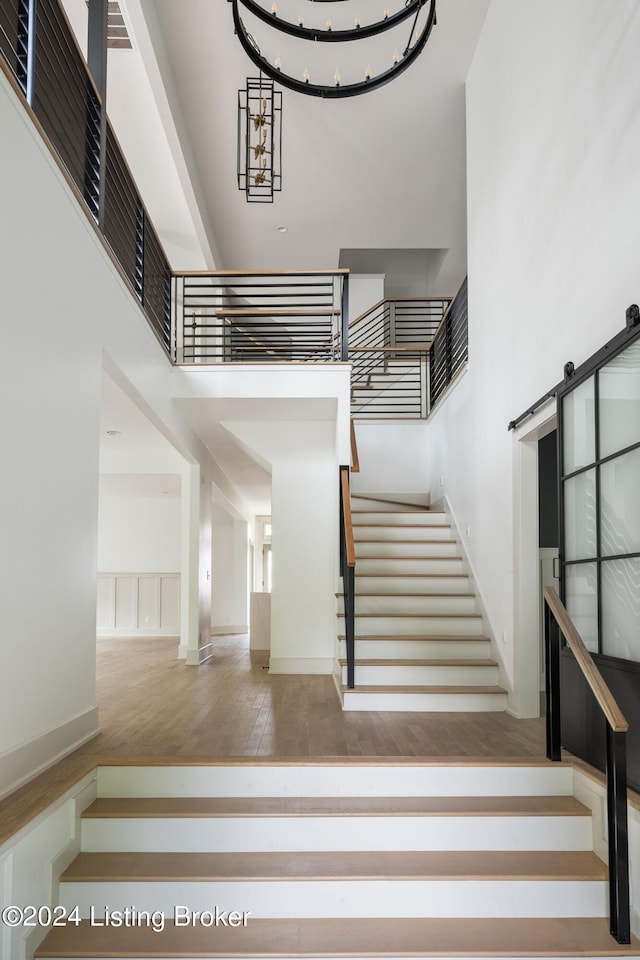 stairs with hardwood / wood-style floors, a towering ceiling, and a barn door