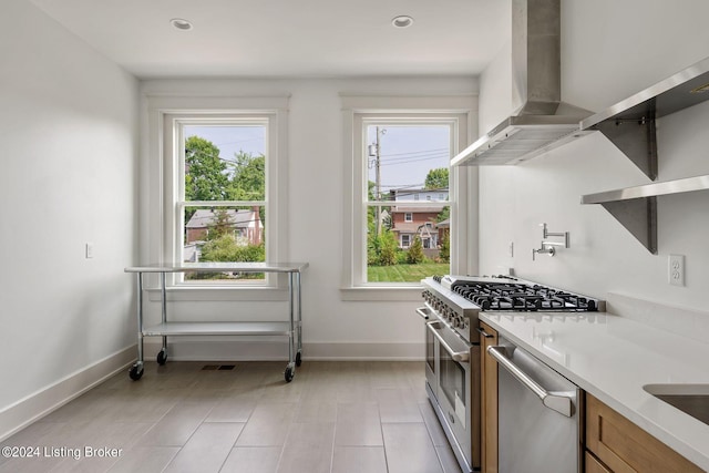 kitchen with appliances with stainless steel finishes, a healthy amount of sunlight, and wall chimney exhaust hood