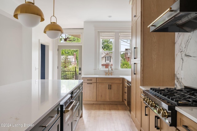 kitchen with hanging light fixtures, sink, backsplash, extractor fan, and stainless steel cooktop