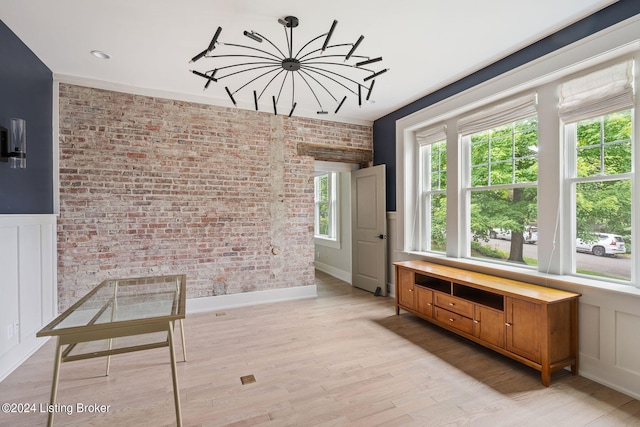 unfurnished dining area featuring brick wall, light wood-type flooring, and a wealth of natural light