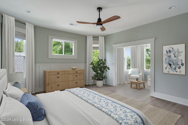 bedroom featuring ceiling fan, light wood-type flooring, and multiple windows