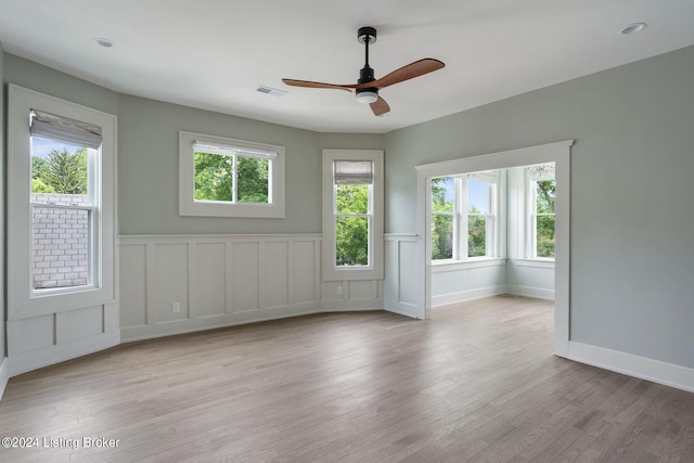 unfurnished room featuring a healthy amount of sunlight, light hardwood / wood-style floors, and ceiling fan