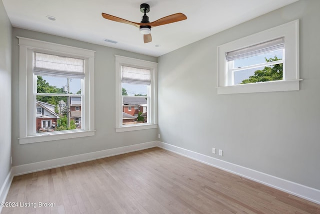 empty room with light wood-type flooring, ceiling fan, and a wealth of natural light