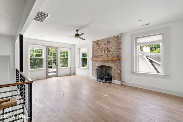 unfurnished living room with light wood-type flooring, a fireplace, and plenty of natural light