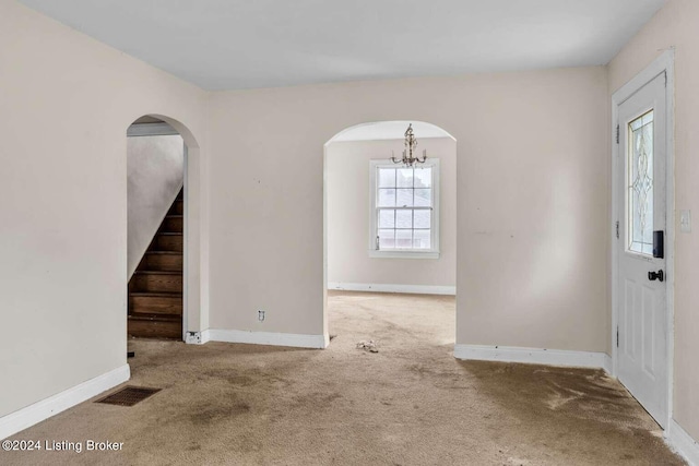 carpeted entrance foyer with a chandelier