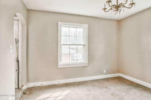 carpeted empty room with a chandelier