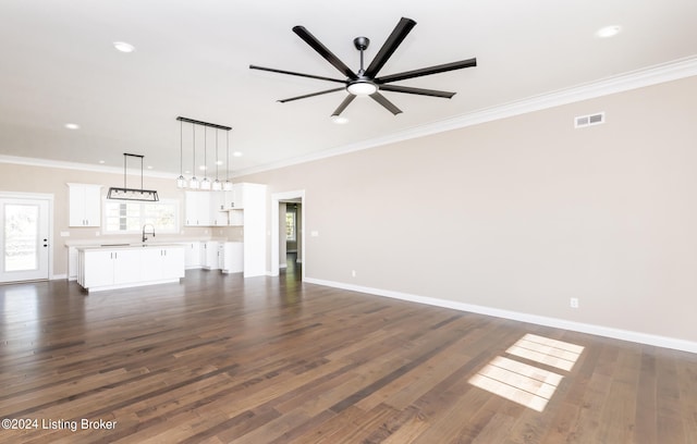 unfurnished living room with ceiling fan, dark wood-type flooring, and ornamental molding