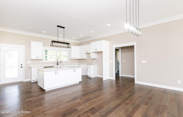 kitchen with white cabinetry, crown molding, a kitchen island, and dark hardwood / wood-style floors