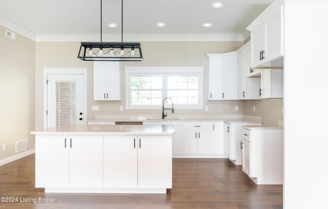 kitchen featuring white cabinetry, a center island, sink, dark wood-type flooring, and ornamental molding