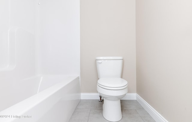 bathroom featuring tile patterned flooring, a bathing tub, and toilet