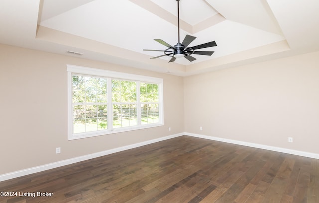 spare room featuring ceiling fan, dark wood-type flooring, and a tray ceiling