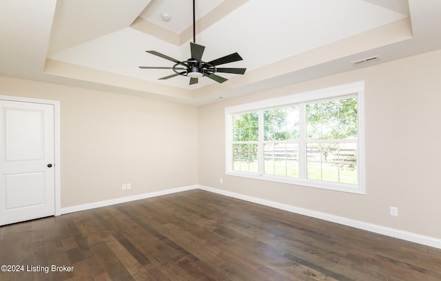 spare room with plenty of natural light, dark hardwood / wood-style flooring, and a tray ceiling