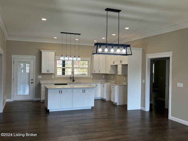 kitchen with a center island, white cabinets, dark hardwood / wood-style floors, ornamental molding, and decorative light fixtures