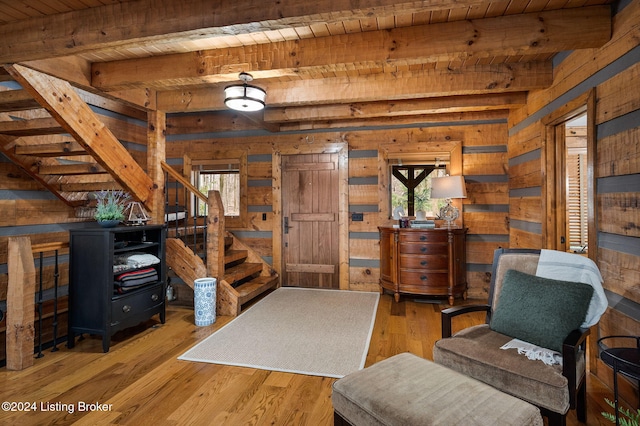 living area with beam ceiling, wooden ceiling, wooden walls, and light hardwood / wood-style flooring