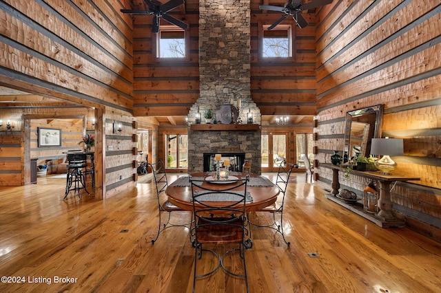 dining room featuring hardwood / wood-style floors, ceiling fan, a towering ceiling, and a fireplace