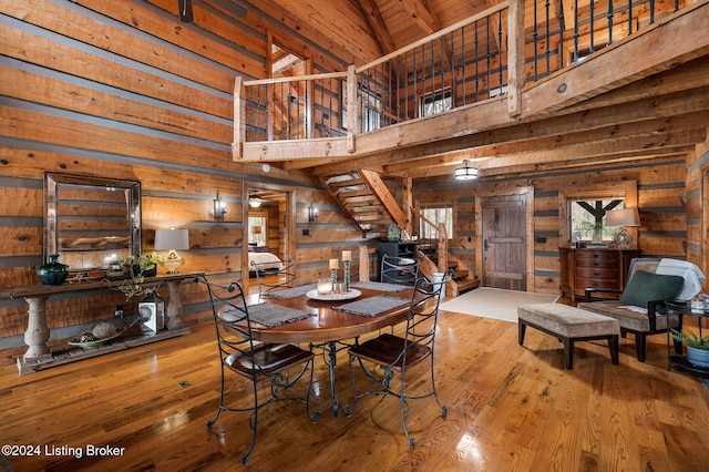 dining space featuring beam ceiling, wooden ceiling, high vaulted ceiling, wood walls, and hardwood / wood-style floors