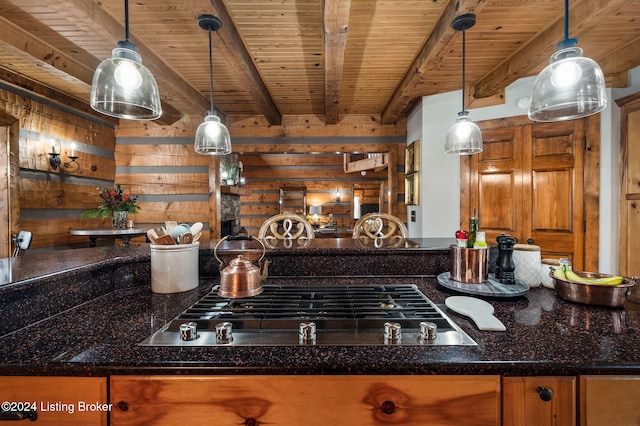 kitchen featuring pendant lighting, stainless steel gas stovetop, dark stone counters, and beam ceiling