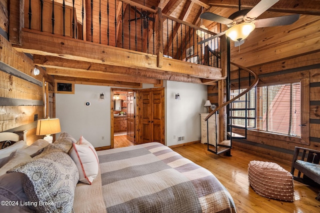 bedroom featuring beam ceiling, light hardwood / wood-style flooring, high vaulted ceiling, wooden walls, and wood ceiling