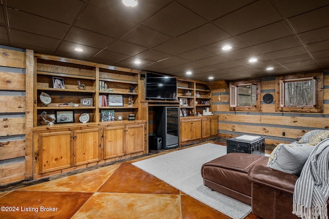 living room featuring a drop ceiling and wooden walls