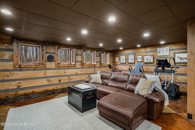 living room featuring a drop ceiling and wooden walls