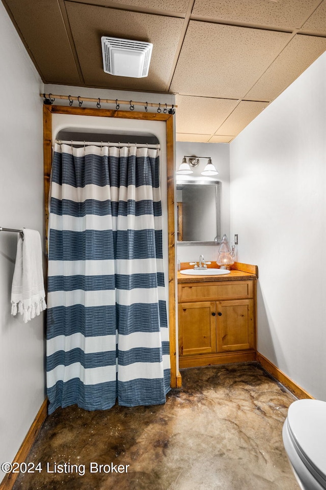 bathroom with vanity, concrete floors, toilet, and a paneled ceiling