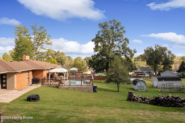 view of yard featuring a storage shed, a deck, and an outdoor fire pit