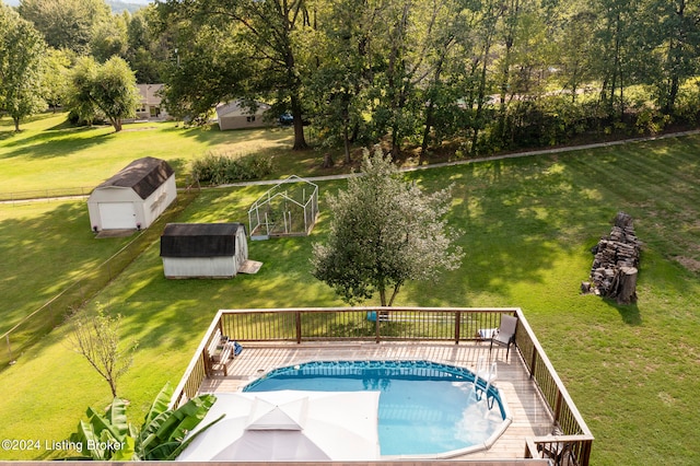 view of pool featuring a wooden deck, a storage shed, and a lawn