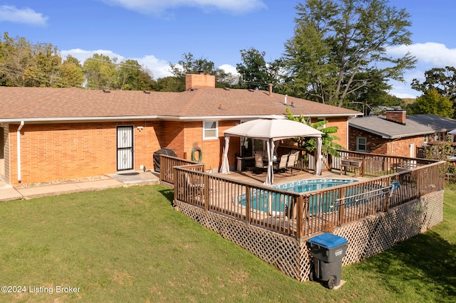 rear view of property featuring a gazebo, a deck, and a lawn