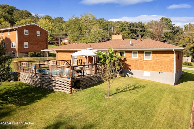 rear view of property featuring a lawn, a gazebo, and a deck