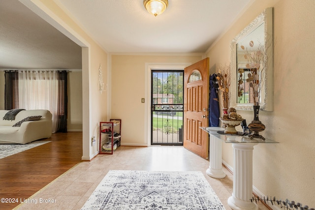 foyer entrance with crown molding and light hardwood / wood-style floors