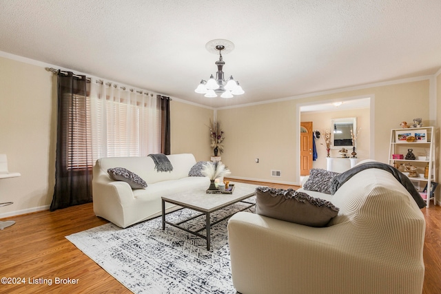 living room with light hardwood / wood-style flooring, ornamental molding, a textured ceiling, and an inviting chandelier