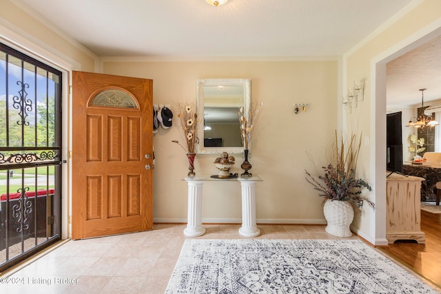 entryway featuring a notable chandelier, light hardwood / wood-style floors, and crown molding