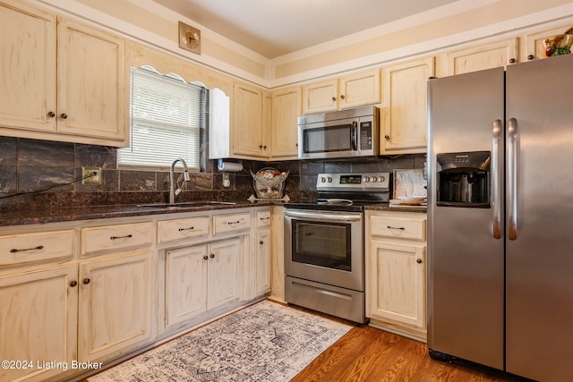 kitchen featuring light brown cabinets, sink, dark wood-type flooring, appliances with stainless steel finishes, and dark stone countertops