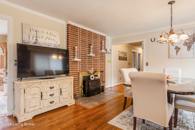 dining space featuring a notable chandelier, a wood stove, hardwood / wood-style flooring, and ornamental molding