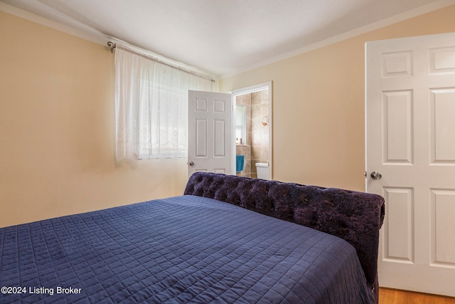 bedroom with ensuite bathroom and hardwood / wood-style flooring