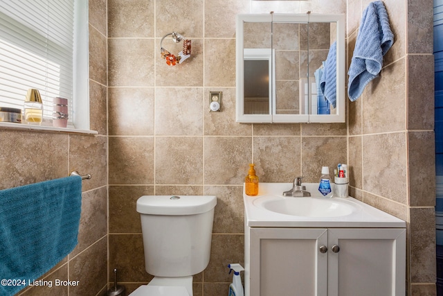 bathroom with tile walls, vanity, and toilet