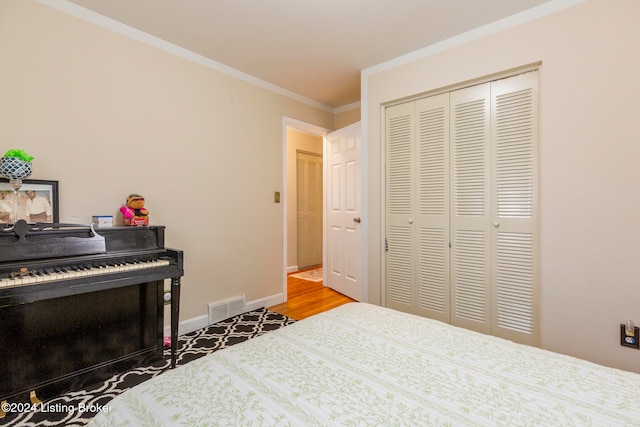 bedroom with wood-type flooring, ornamental molding, and a closet